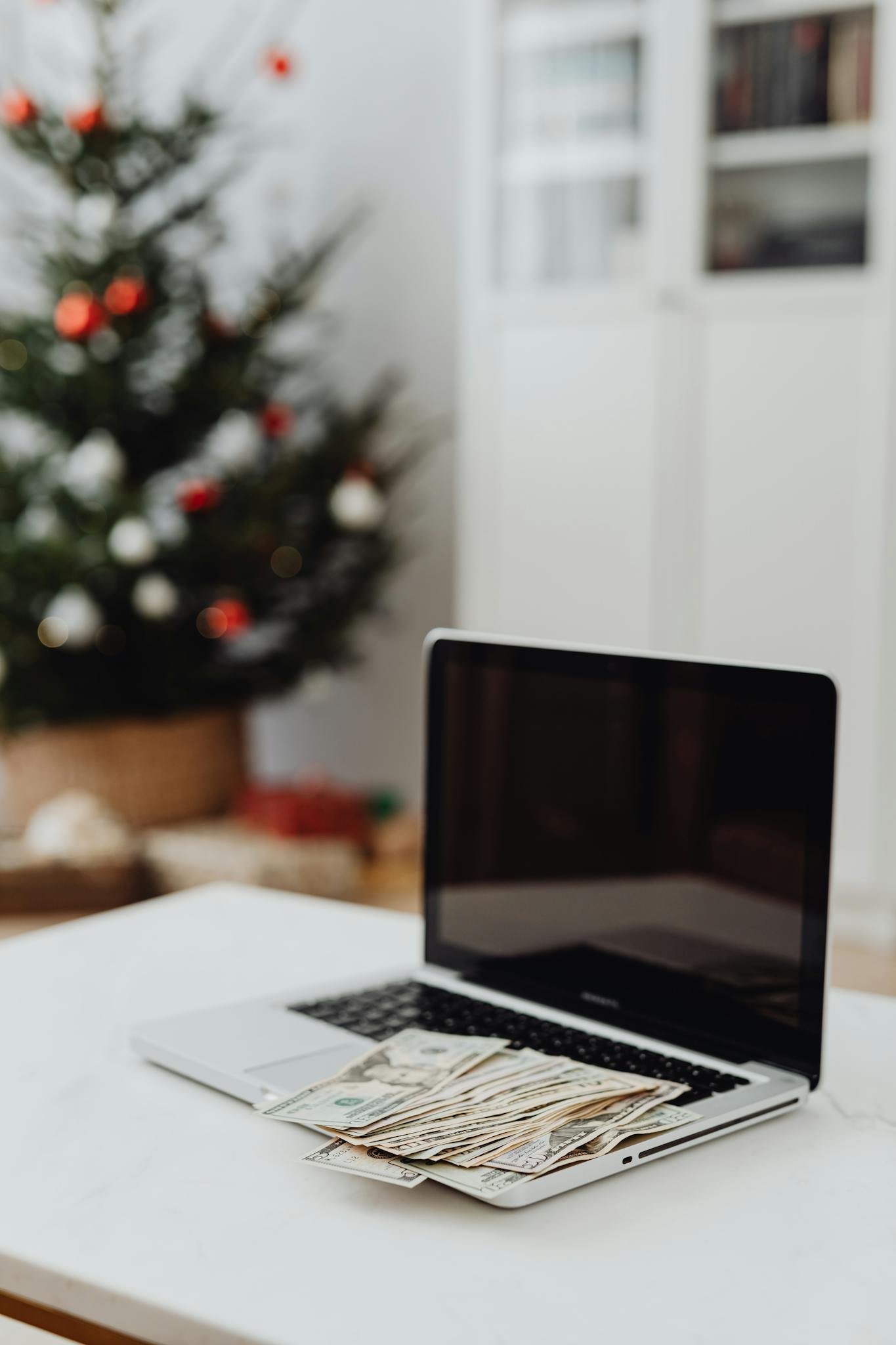 Laptop with cash in a home office decorated for the holidays.
