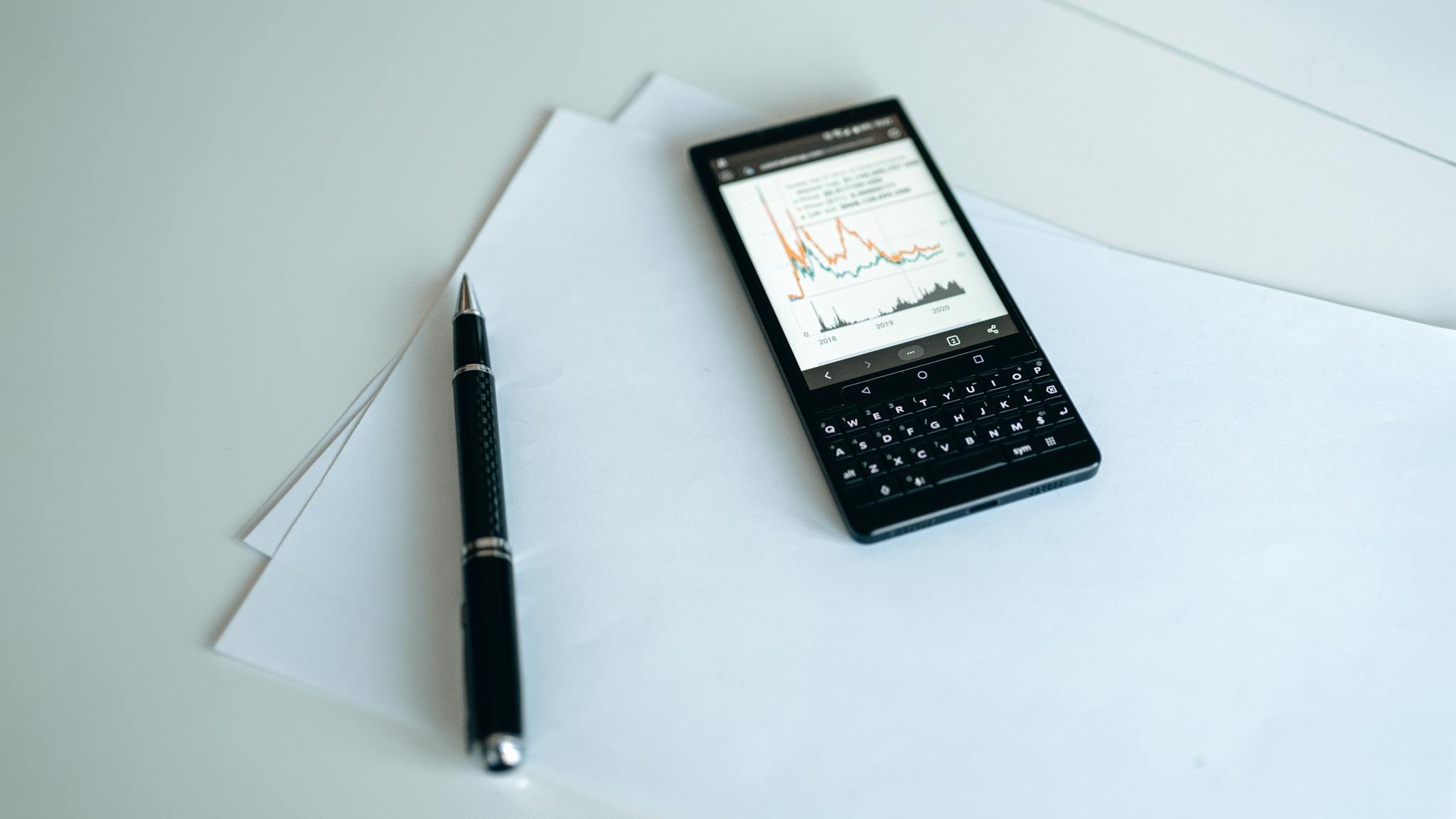 Smartphone displaying graphs on paper with a pen, perfect for business strategy concepts.